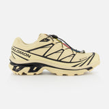 The SALOMON XT-6 GTX Sneaker, shown in side profile on a white background, features a beige design with black accents, rugged sole, and quick-lace system for versatile performance.