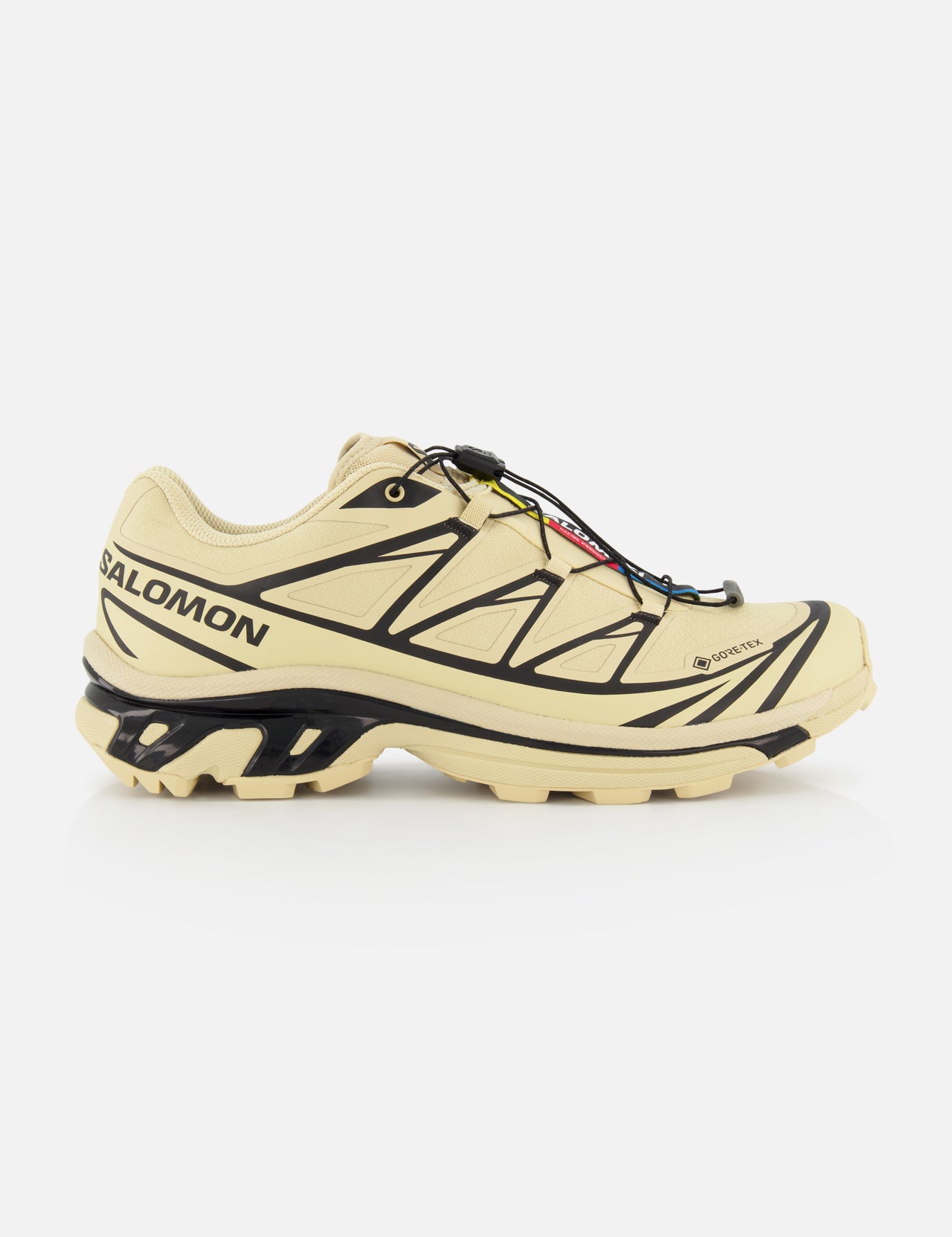 The SALOMON XT-6 GTX Sneaker, shown in side profile on a white background, features a beige design with black accents, rugged sole, and quick-lace system for versatile performance.