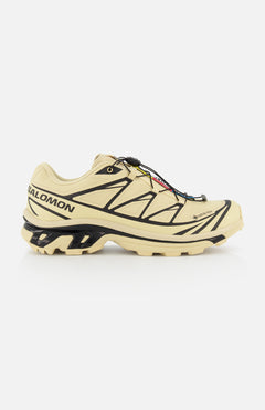 The SALOMON XT-6 GTX Sneaker, shown in side profile on a white background, features a beige design with black accents, rugged sole, and quick-lace system for versatile performance.