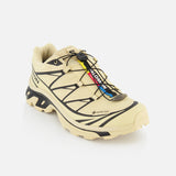 The SALOMON XT-6 GTX Sneaker, shown on a white background, features a beige waterproof Gore-Tex upper, black accents, a quick lace system, and rugged treads for trail running.