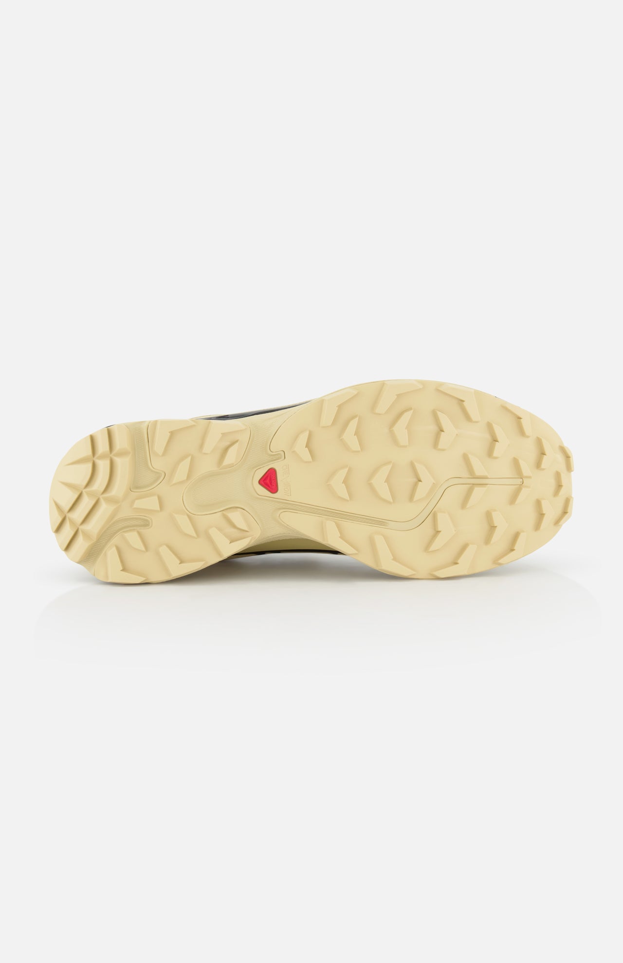 The image displays the beige, textured rubber outsole of the SALOMON XT-6 GTX Sneaker. It features deep treads, a small red triangular logo at the center, and is photographed against a white background.
