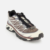 The SALOMON XT-6 Shadow Sneaker is a single ultra-distance race shoe showcasing a white, black, and brown pattern, finished with black laces and a rugged black sole for exceptional durability and cushioning, displayed on a white background.