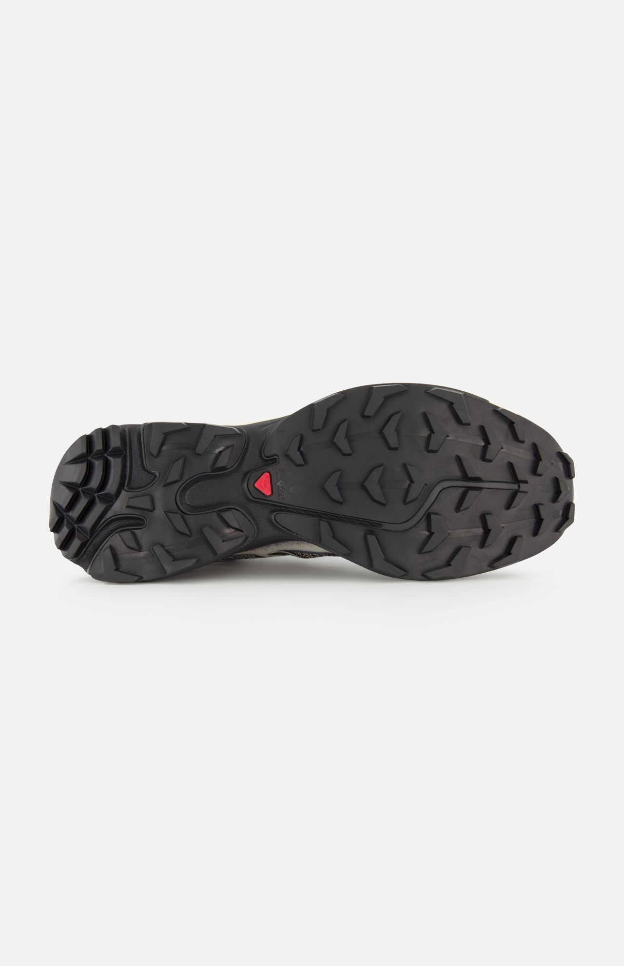 The image displays the black rubber outsole of the SALOMON XT-6 Shadow Sneaker, featuring a rugged traction pattern for enhanced durability and a small red triangular detail at the center.