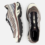 Two SALOMON XT-6 Shadow Sneakers in beige, brown, and black are displayed from side and top perspectives, highlighting their rugged soles for enhanced durability and advanced quick-lace systems. Designed with responsive cushioning for ultra-distance racing, these shoes are set against a plain white background.