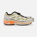 Salomon XT-6 sneaker in olive green and white, featuring an orange midsole, durable construction, and a quick-lace system.