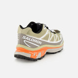 Olive green Salomon XT-6 sneaker featuring a bright orange midsole, durable construction, and a quick-lace system.