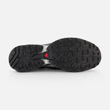 The image shows the black rubber outsole of the SALOMON XT-Pathway GTX Sneaker, featuring a textured grip and a small red triangle near the arch—designed for optimal traction in ultra-distance races. The background is plain white.