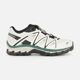 Side view of the SALOMON XT-Quest Sneaker in white and black, featuring a rugged black sole, green-gray accents, and lace-up closure; this hybrid performance sneaker is designed to blend urban wearability with enhanced stability and grip, shown against a plain white background.