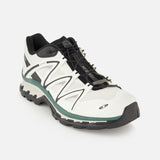 Introducing the SALOMON XT-Quest Sneaker—a white and black hybrid performance shoe featuring a low-profile design, resilient black sole, breathable mesh fabric, and quick-pull lacing system. Engineered to deliver both urban wearability and exceptional stability and grip for trail runs, this athletic sneaker is showcased against a plain white background.