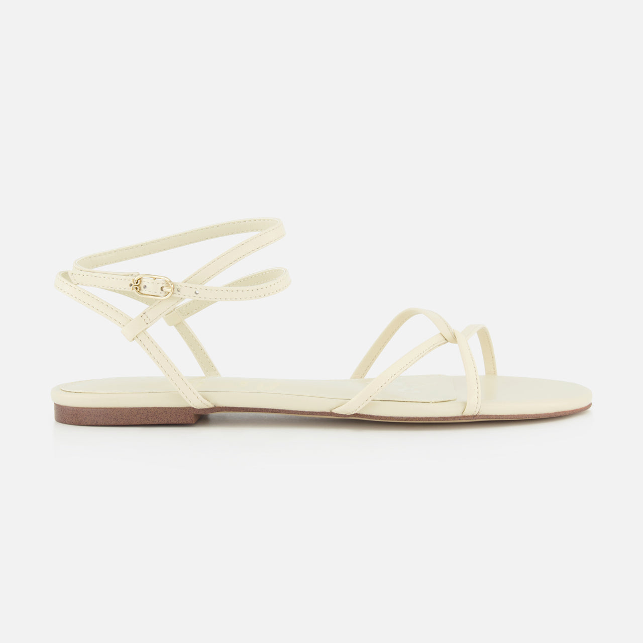 The Ellina Strappy Flat Sandal by SAM EDELMAN is a minimalist off-white sandal with thin crisscross straps, a small ankle buckle, and a cushioned footbed for all-day comfort.