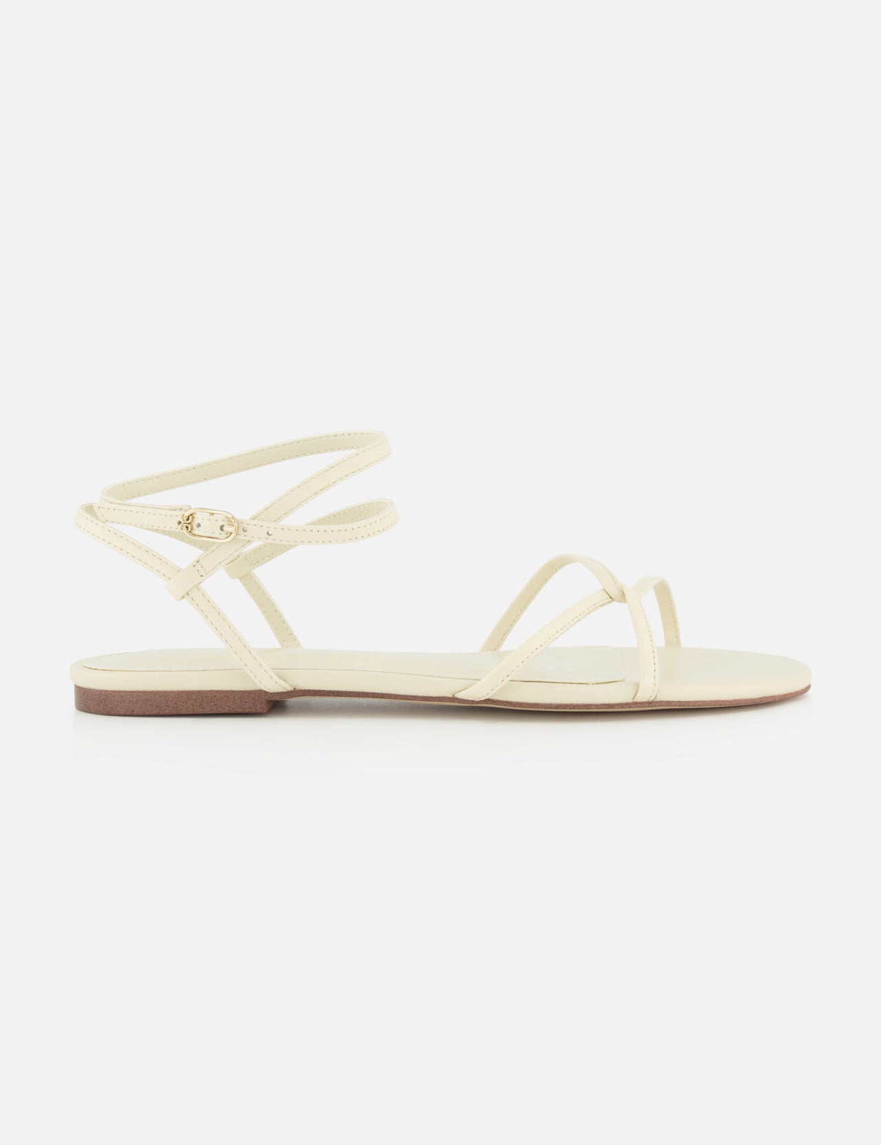 The Ellina Strappy Flat Sandal by SAM EDELMAN is a minimalist off-white sandal with thin crisscross straps, a small ankle buckle, and a cushioned footbed for all-day comfort.