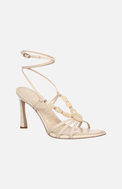 The SAM EDELMAN Imani Heeled Gemstone Sandal features off-white beaded straps and a slender ankle strap, adding a touch of elegance and subtle sophistication to any outfit. Perfect for refined style.