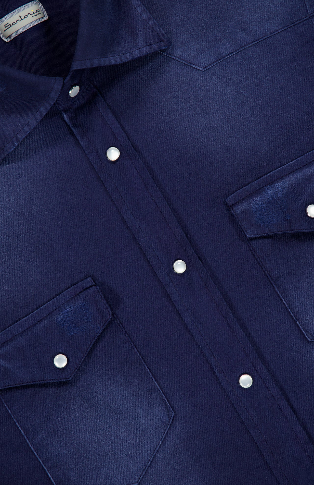 Close-up of a SARTORIO Distressed Cotton Button Up Shirt in dark blue, featuring snap buttons, two chest pockets, and a slight fabric sheen. The brand label appears at the collar.