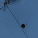 Close-up of a blue button-up shirt with two black buttons visible and gray inner lining near the collar, styled underneath the SARTORIO Double Faced Overcoat.