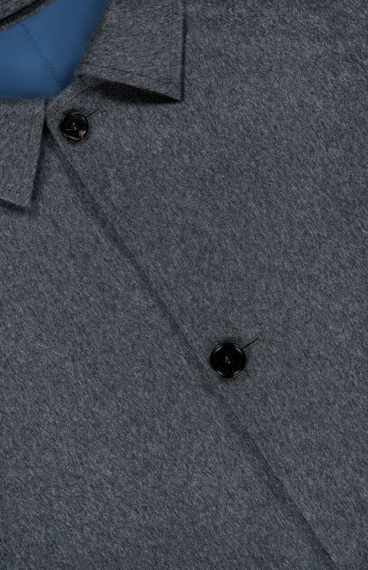 Close-up of a grey wool shirt with two black buttons and a pointed collar, with a glimpse of blue inner lining at the top left corner—an ideal match for the SARTORIO Double Faced Overcoat, expertly crafted in Italy.