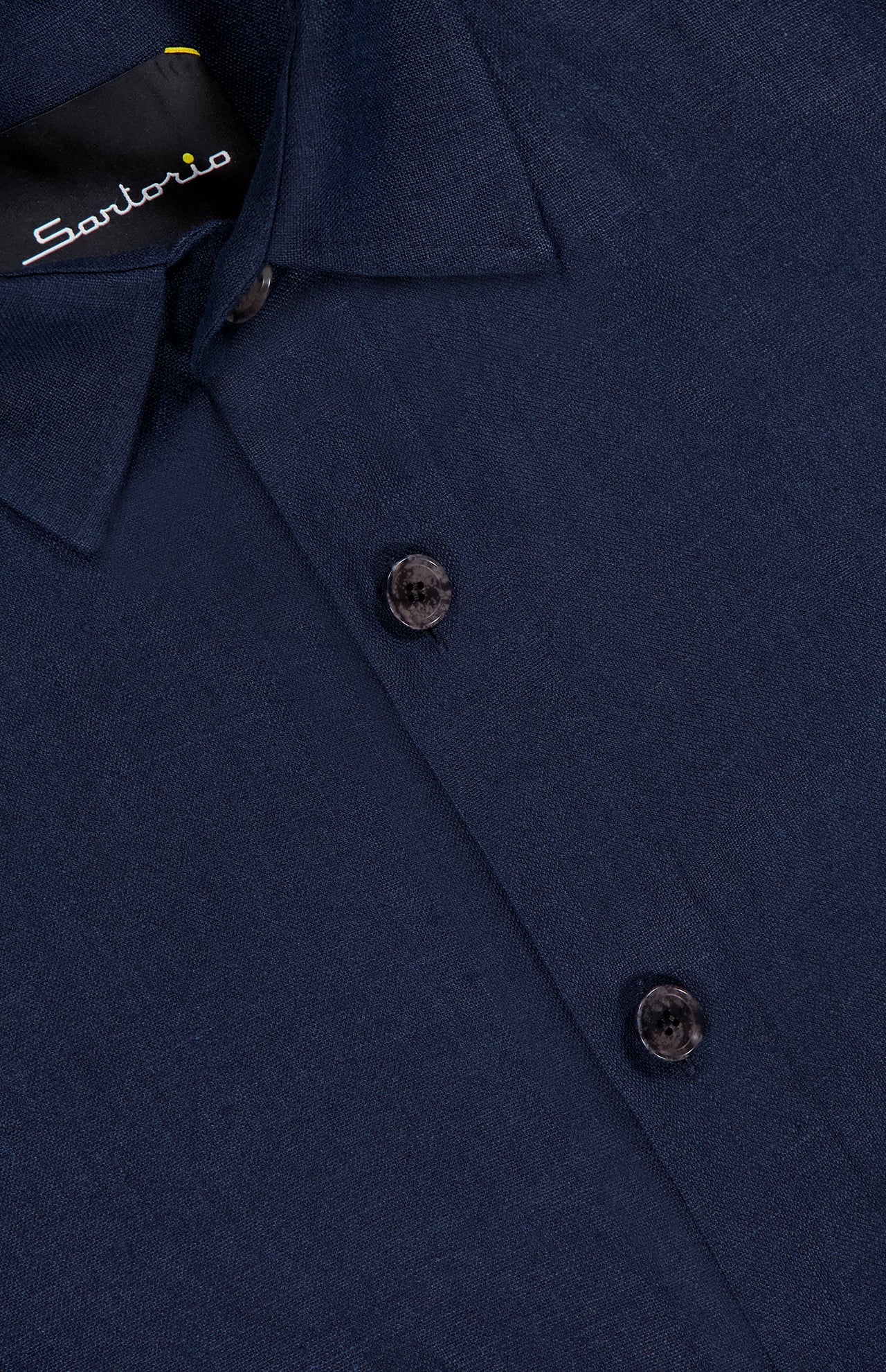 Close-up of the SARTORIO Linen Flap Pocket Overshirt in navy, showing two buttons and part of the label with "SARTORIO" in white text, made in Italy.
