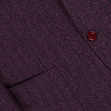 Close-up of the SARTORIO Wool Herringbone Sportcoat in purple, showcasing its expert craftsmanship with a distinct herringbone pattern. Features include two maroon buttons, a pocket, and visible stitching.