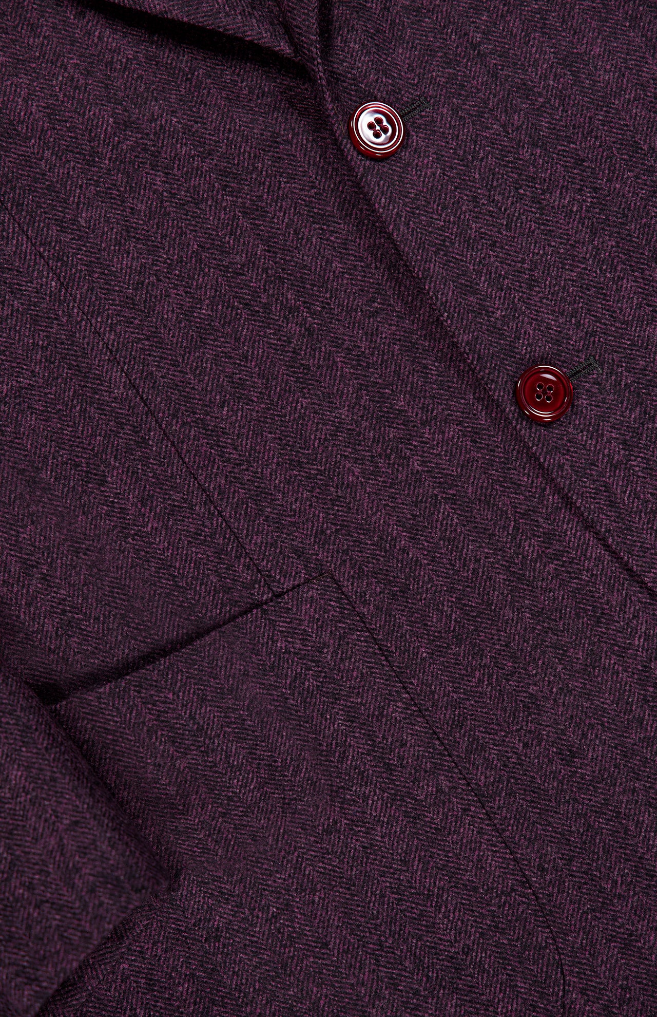 Close-up of the SARTORIO Wool Herringbone Sportcoat in purple, showcasing its expert craftsmanship with a distinct herringbone pattern. Features include two maroon buttons, a pocket, and visible stitching.