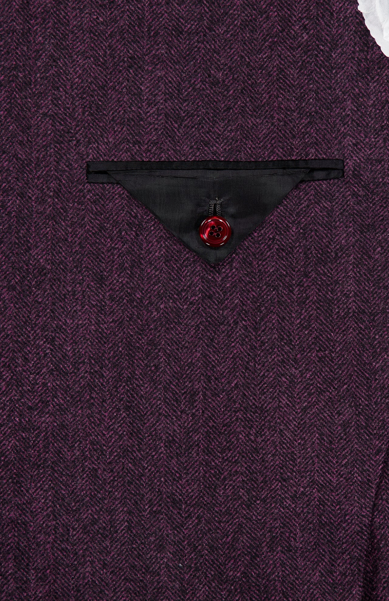 Close-up of the SARTORIO Wool Herringbone Sportcoat in purple, featuring a herringbone pattern, a pocket with black trim, and a bold red button centered on the pocket flap. Made in Italy.