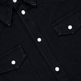 Close-up of the SAVAS Allen Denim Shirt in dark Japanese selvedge denim, featuring white snap buttons, a pointed collar, and two front chest pockets. The shirt tag is partially visible in the upper left corner.