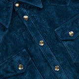 Close-up of the SAVAS Lowry Calf Suede Overshirt in blue, featuring metal snap buttons and two chest pockets. A partially visible leather tag with embossed text at the top left accentuates its refined Western-inspired style.
