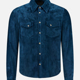 Introducing the Lowry Calf Suede Overshirt by SAVAS—a timeless, Italian-made western shirt crafted from luxurious blue calf suede. This long-sleeve overshirt showcases two chest pockets with button flaps, a pointed collar, and silver buttons down the front for a classic finishing touch.