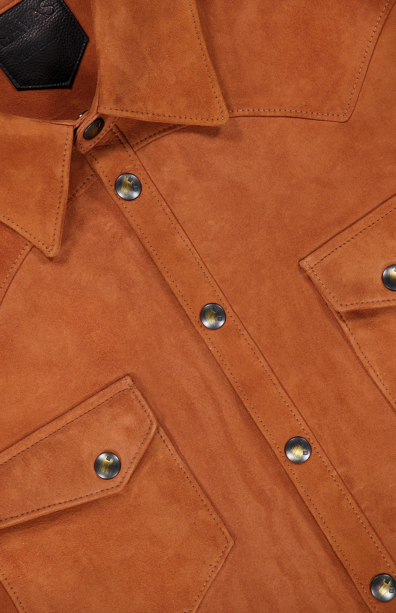 Close-up of the SAVAS Lowry Lamb Suede Overshirt, crafted in brown lamb suede with metal snap buttons, two front flap pockets, and detailed visible stitching. This premium overshirt is expertly made in Italy.