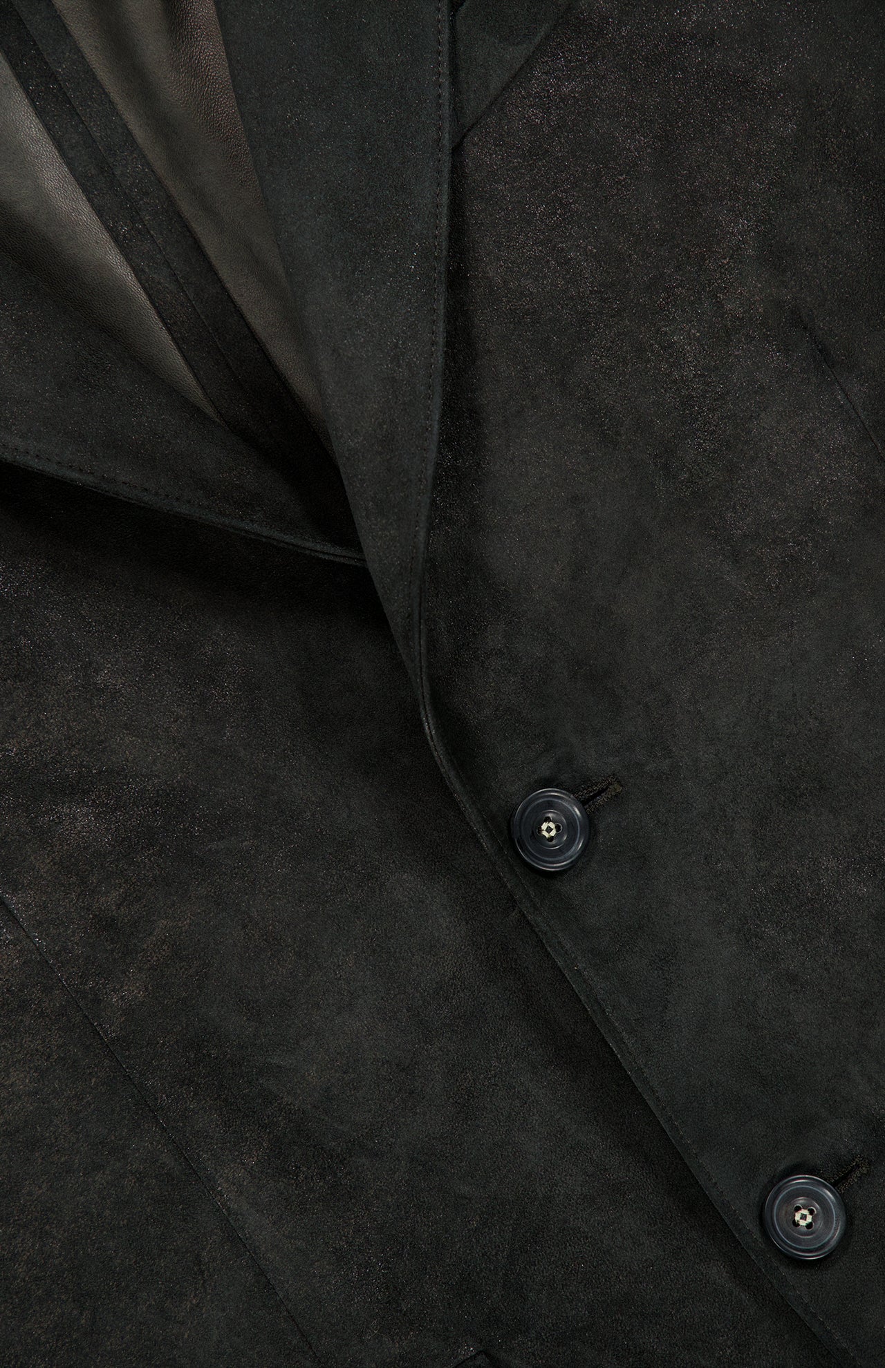Close-up of the Owens Lamb Leather Blazer by SAVAS, highlighting two buttons, part of the collar, and the textured leather. The photo accentuates the smooth, matte finish and precise stitching details, capturing a handcrafted artisanal style reminiscent of luxury Italian craftsmanship.