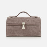 The Symmetry Pouchette Bag by Savette is a taupe suede handbag featuring a rectangular silhouette, top handle, and silver front clasp, expertly crafted in Italy and photographed against a white background—a refined example of quiet luxury.