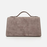 The Symmetry Pouchette Bag by Savette is a rectangular taupe suede handbag with a short top handle, embodying the understated elegance of quiet luxury, shown against a plain white background.