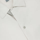Close-up of the SEASE Spring Lifetime Drawcord Jacket, featuring a snap-front closure with silver snap buttons and a gray tag inside the collar, photographed against a white background.