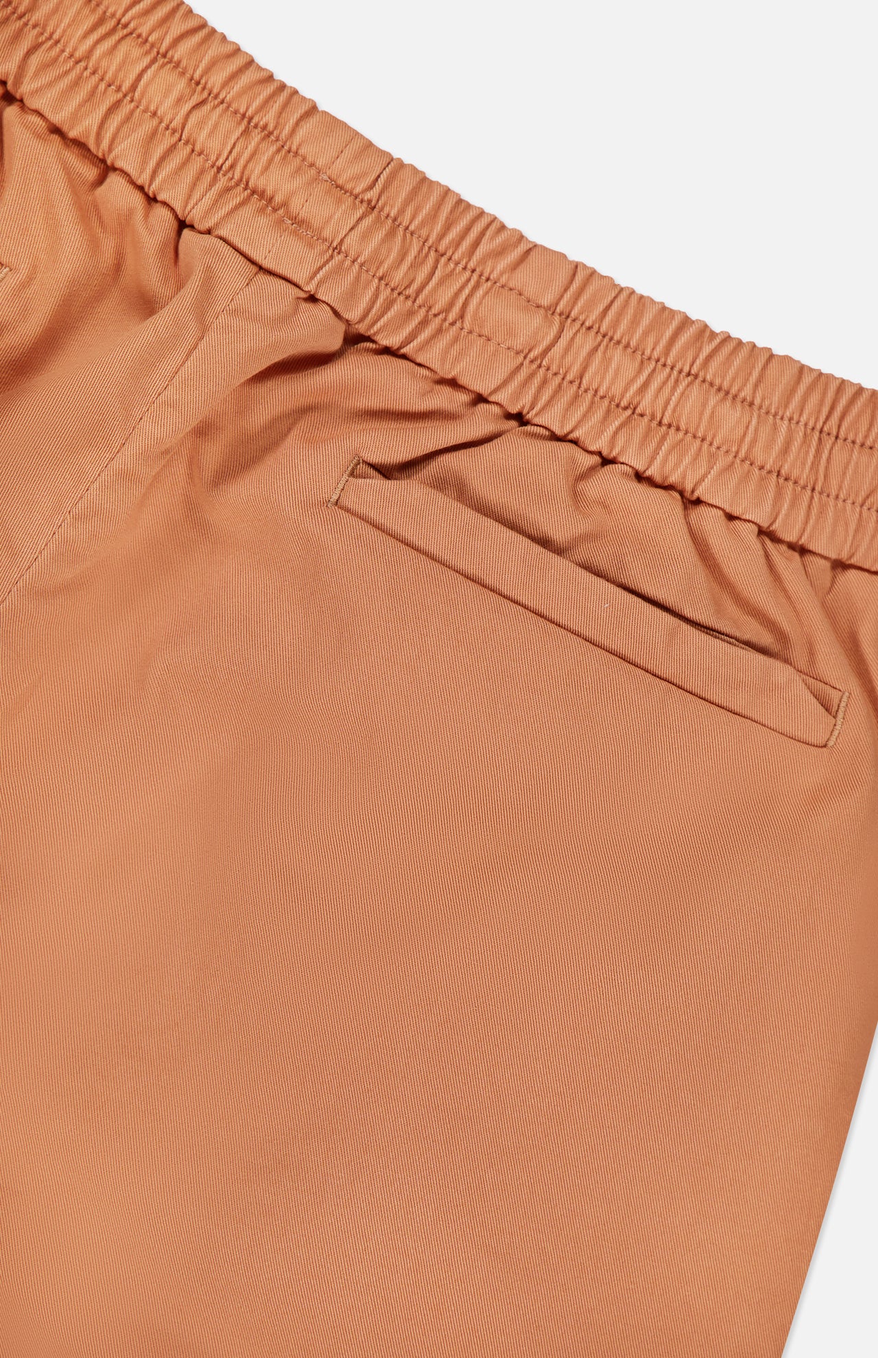 Close-up of SEASE Summer Mindset Drawstring Trouser Pant in pastel tangerine, featuring an elastic waistband and single welt back pocket, set against a white background.