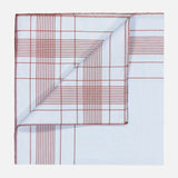 Harlan Cotton Pocket Square in light blue with a red grid pattern and a folded corner, styled in the tradition of a French fashion house.