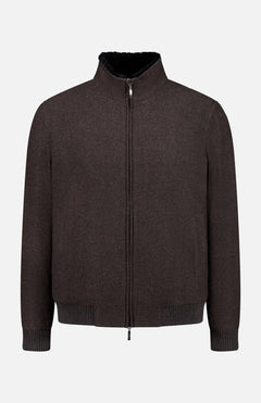 The DORIANI Fur 180′s Jersey Bomber Jacket, a chocolate brown wool piece handcrafted in Italy, features a plush shearling collar lining, ribbed cuffs and hem, and a sleek silver zipper. Presented flat against a white background.