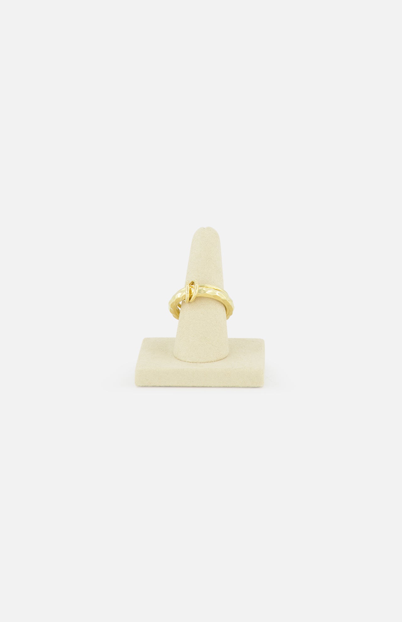 The SPINELLI KILCOLLIN Agon Vulcan Ring, featuring an elegant yellow gold knot design, is displayed on a beige cone stand against a plain white background.