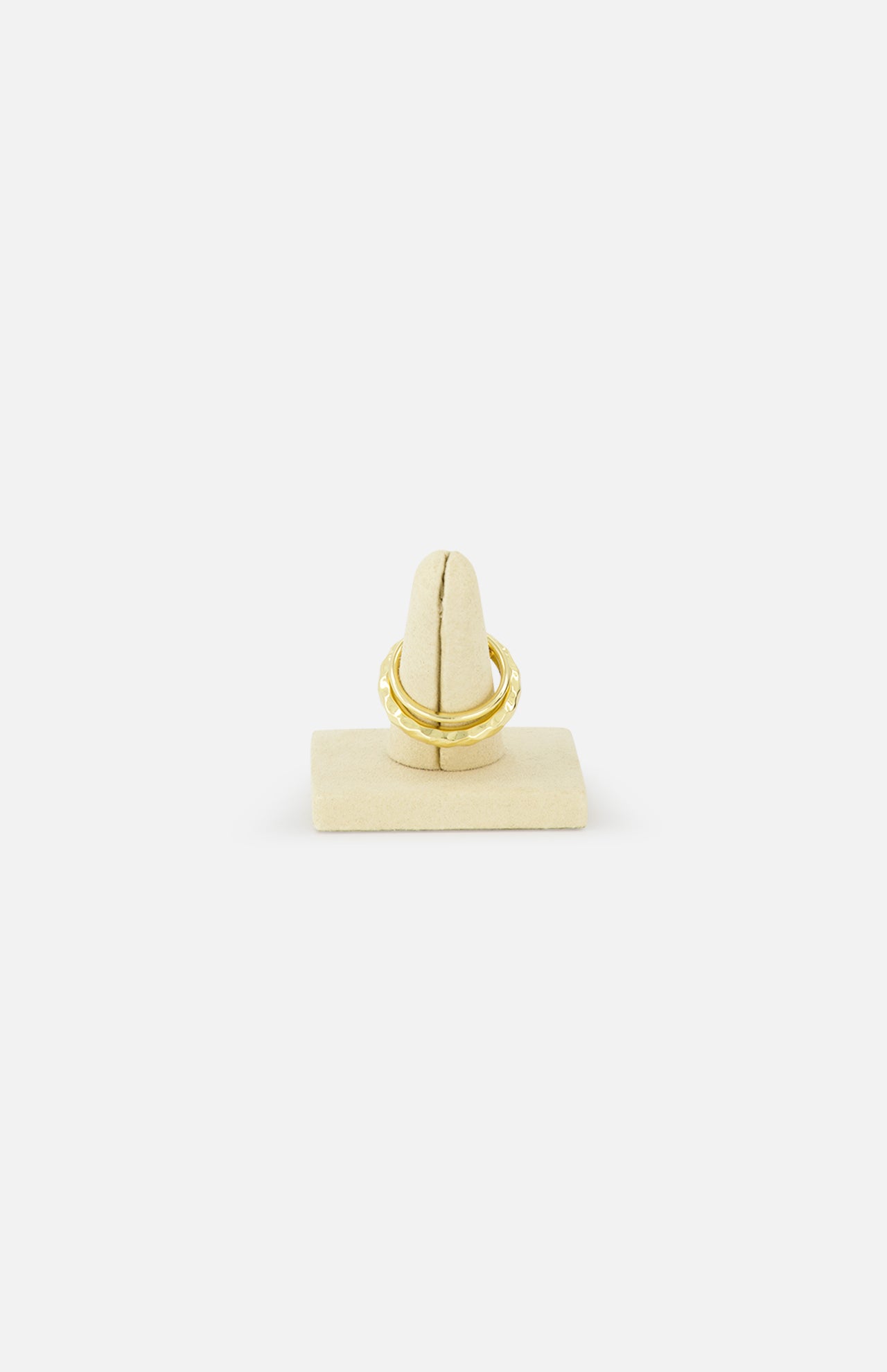 The SPINELLI KILCOLLIN Agon Vulcan Ring, crafted in yellow gold, is displayed on a beige velvet ring stand against a white background, highlighting its elegant, fluid design.