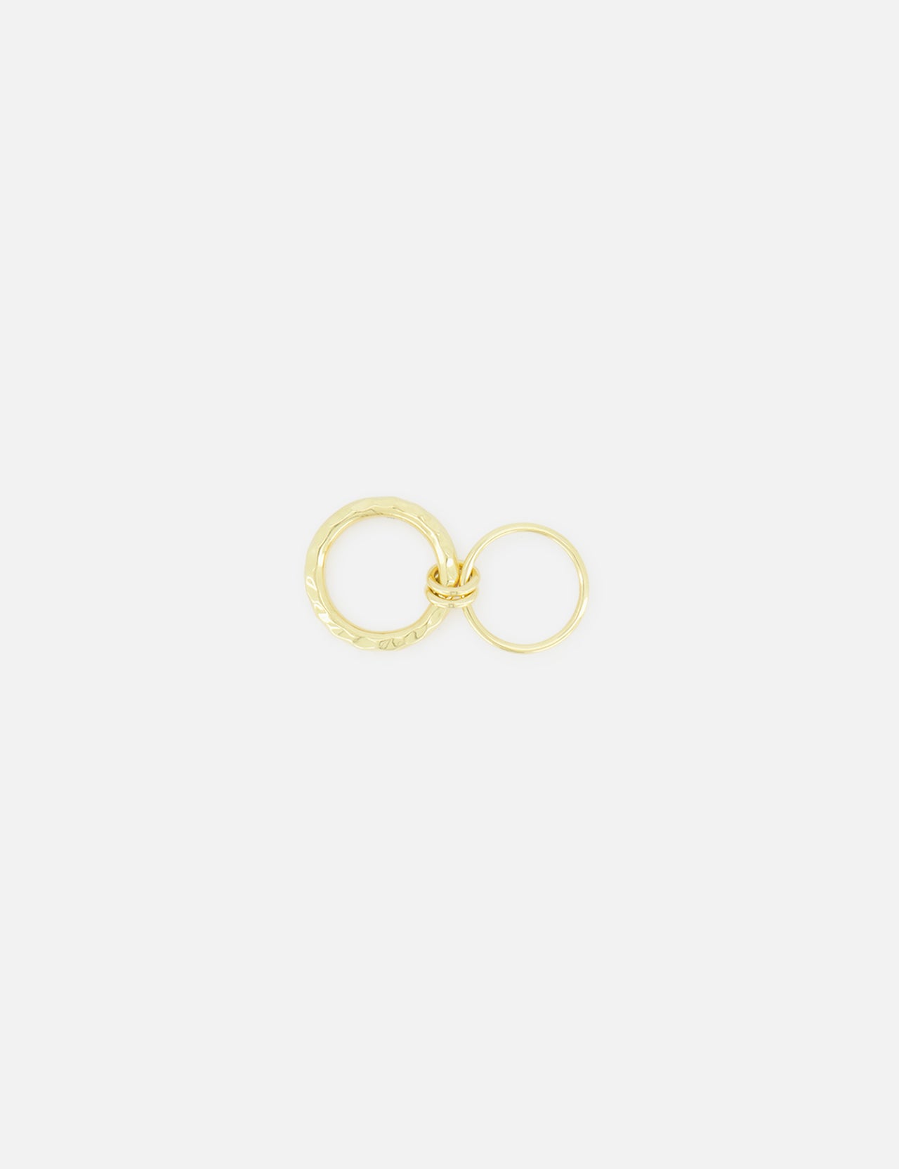 Two yellow gold Agon Vulcan Rings by SPINELLI KILCOLLIN, each in a different size with fluid designs, are interlinked and set against a plain white background.