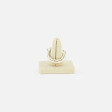The Microdame SK Ring by SPINELLI KILCOLLIN, inspired by modular jewelry, is displayed on a beige stand against a plain white background.