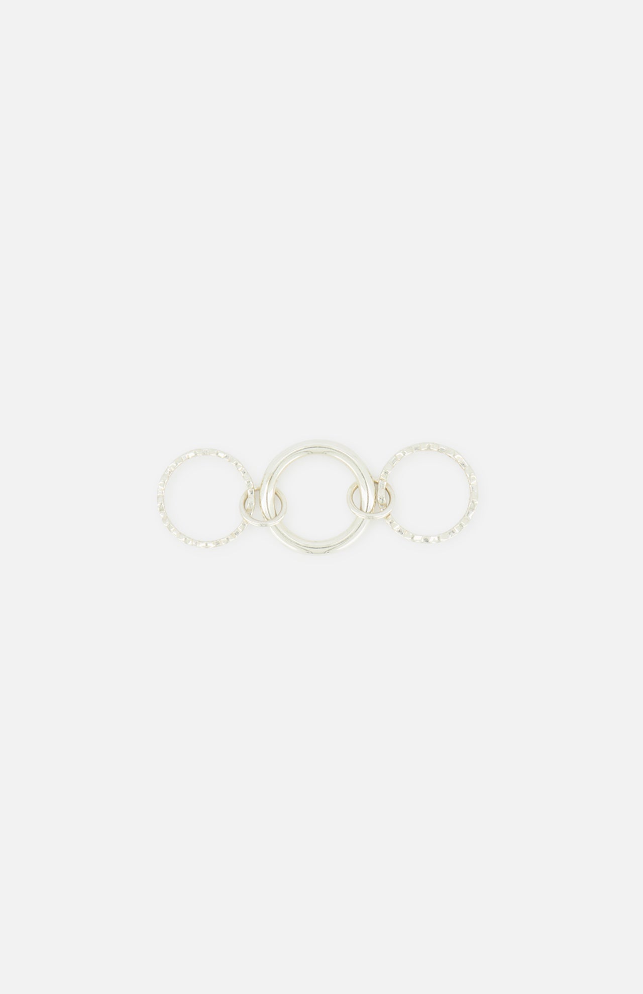 The SPINELLI KILCOLLIN Microdame SK Ring features three interlocking sterling silver bands: a smooth, solid center ring flanked by two textured, beaded rings, all arranged horizontally on a plain white background.