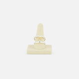 The Phantom SK Ring by SPINELLI KILCOLLIN—featuring a minimalist geometric gold design—is shown upright on a light beige holder, set against a plain white background.