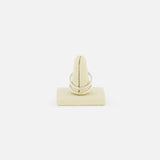 The Phantom SK Ring by SPINELLI KILCOLLIN, a sleek silver modular jewelry piece, is displayed upright on a beige ring holder set against a plain white background.