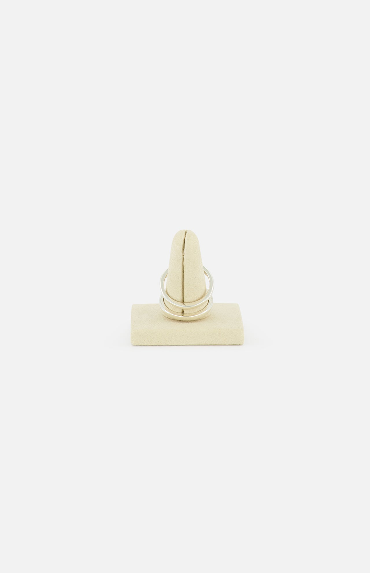 The Phantom SK Ring by SPINELLI KILCOLLIN, a sleek silver modular jewelry piece, is displayed upright on a beige ring holder set against a plain white background.