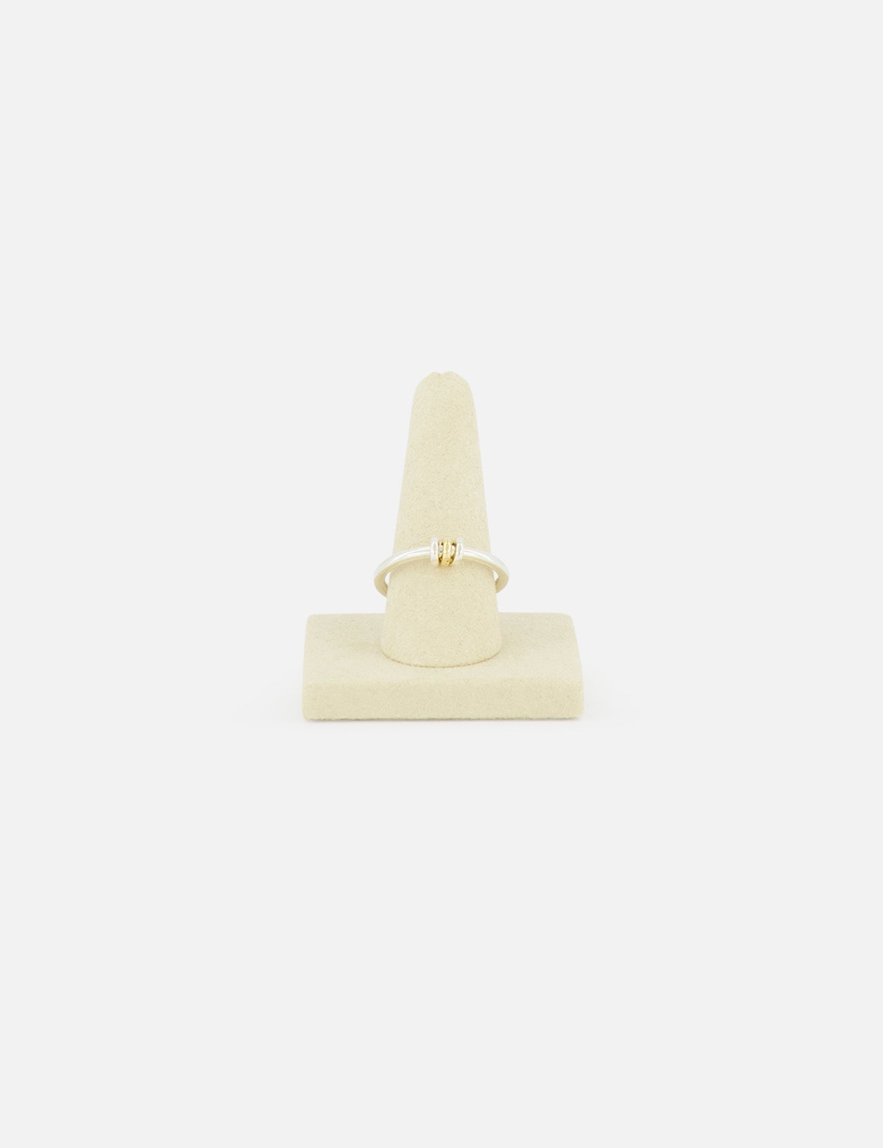 The SPINELLI KILCOLLIN Sirius 3 Annulets Ring, a delicate gold piece with a small rectangular gemstone, is displayed on a beige velvet ring stand against a plain white background.