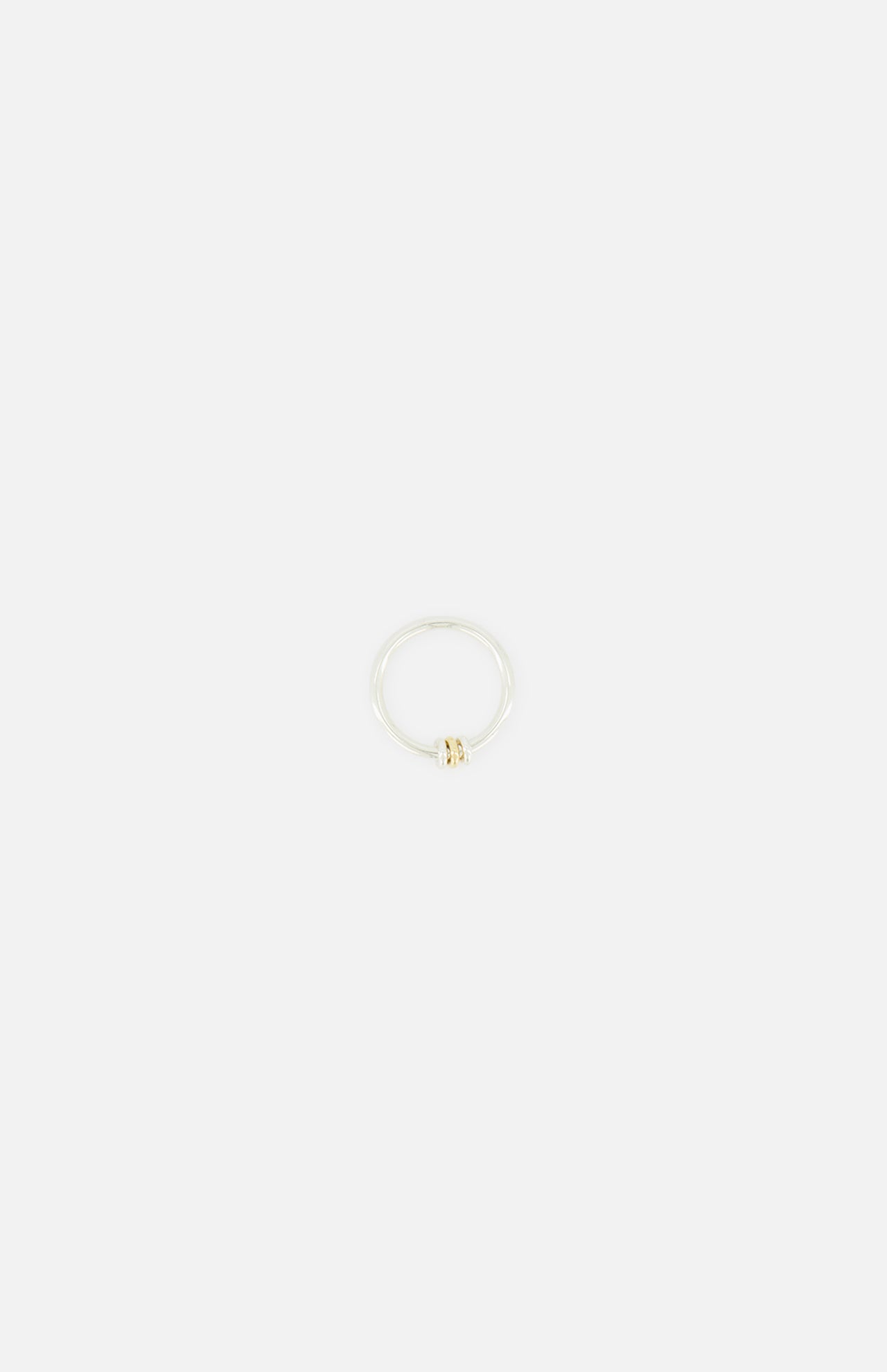 The SPINELLI KILCOLLIN Sirius 3 Annulets Ring features a minimalist sterling silver band with a central small round gold bead, making it an ideal unisex accessory. Shown against a plain white background.