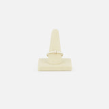 The Sirius 3 Annulets Ring by SPINELLI KILCOLLIN is a delicate, minimalist gold unisex ring with a small design, displayed on a beige suede stand against a plain white background.