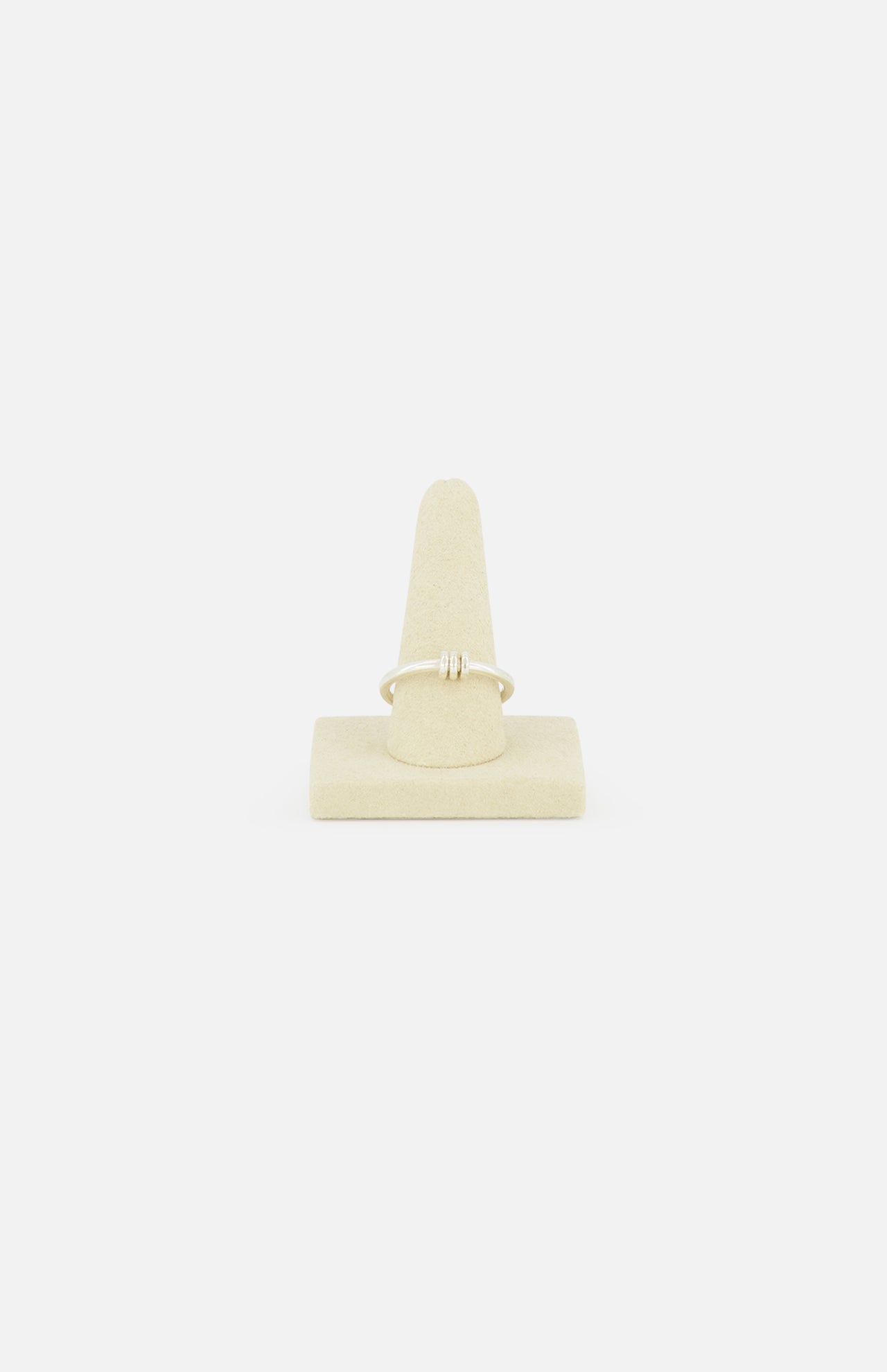 The Sirius 3 Annulets Ring by SPINELLI KILCOLLIN is a delicate, minimalist gold unisex ring with a small design, displayed on a beige suede stand against a plain white background.