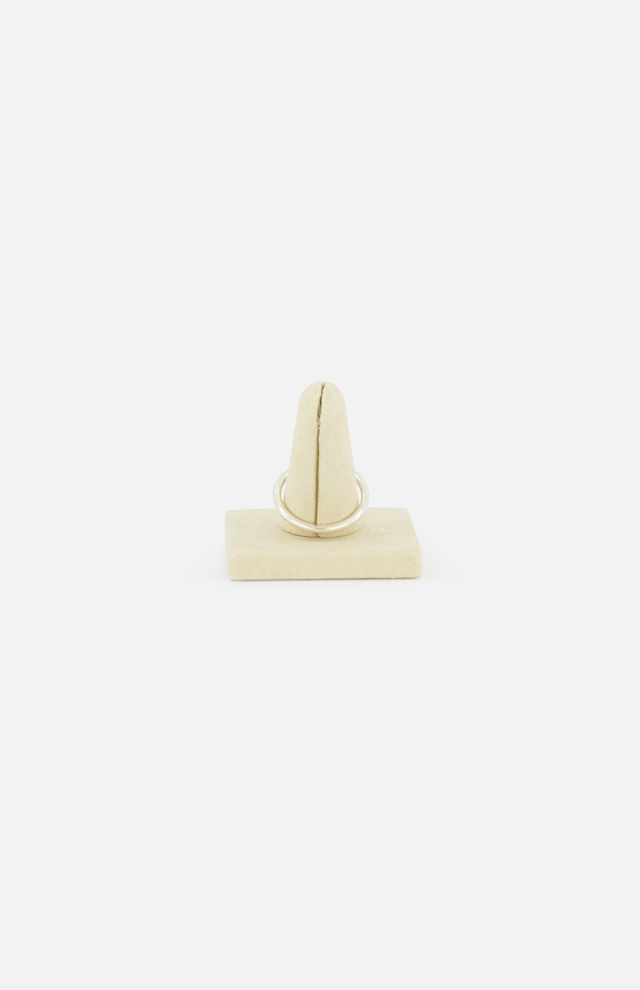 The SPINELLI KILCOLLIN Sirius 3 Annulets Ring, a minimalist unisex design, is displayed upright on a beige velvet ring holder against a plain white background.