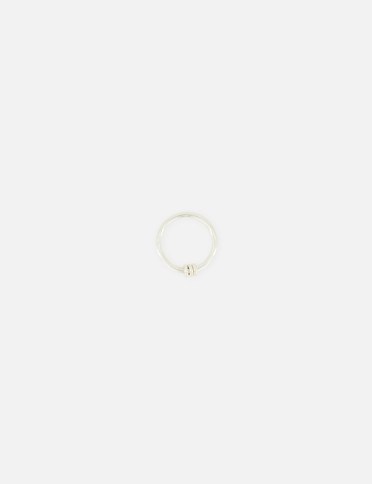 The SPINELLI KILCOLLIN Sirius 3 Annulets Ring is a minimalist unisex sterling silver ring featuring a subtle knot detail, shown against a plain white background.