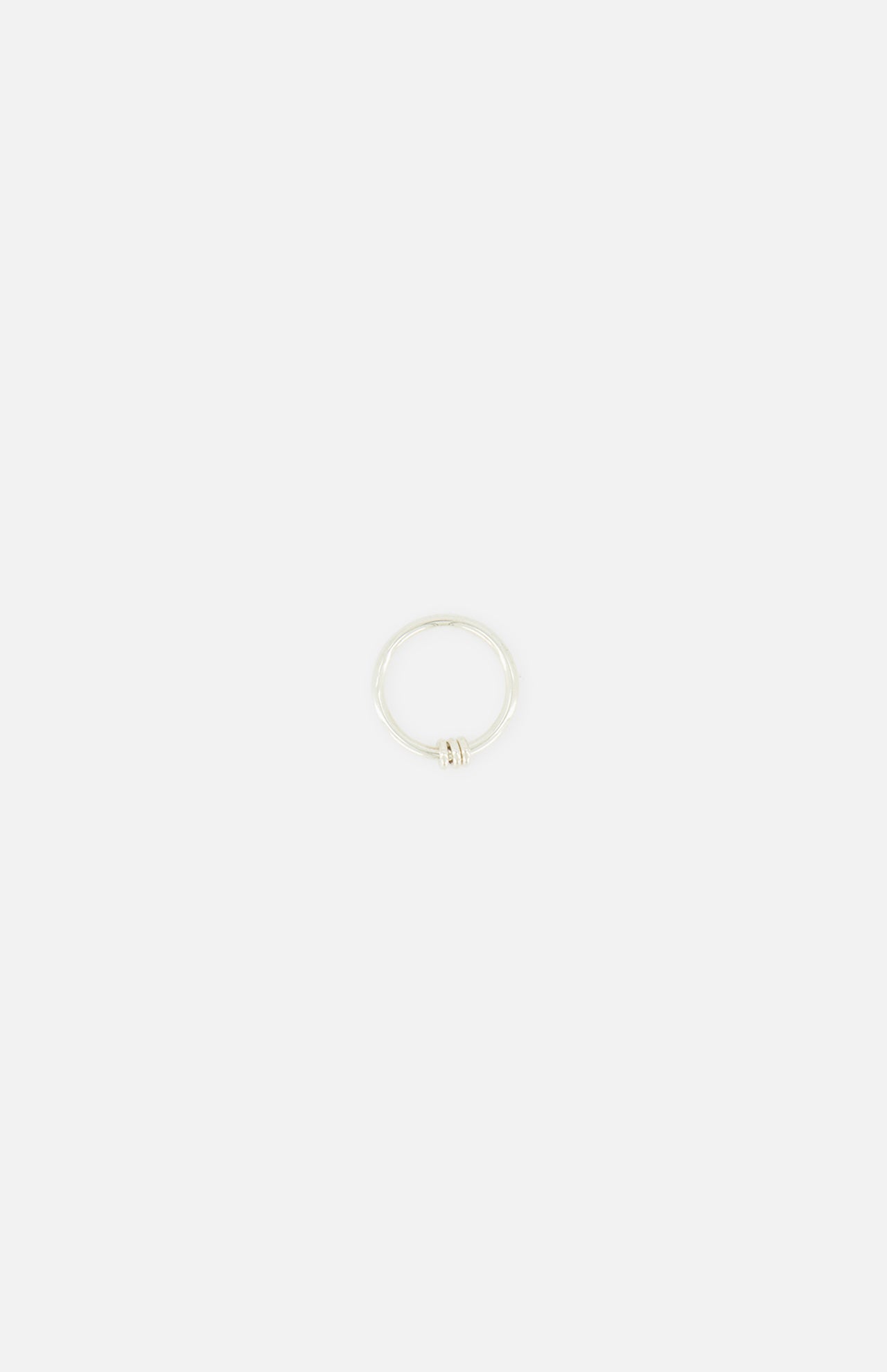 The SPINELLI KILCOLLIN Sirius 3 Annulets Ring is a minimalist unisex sterling silver ring featuring a subtle knot detail, shown against a plain white background.