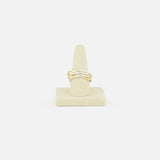 The Solarium SG 3 Band Ring by SPINELLI KILCOLLIN, a minimalist gold twisted band, is displayed on a beige cone-shaped ring holder against a plain white background.